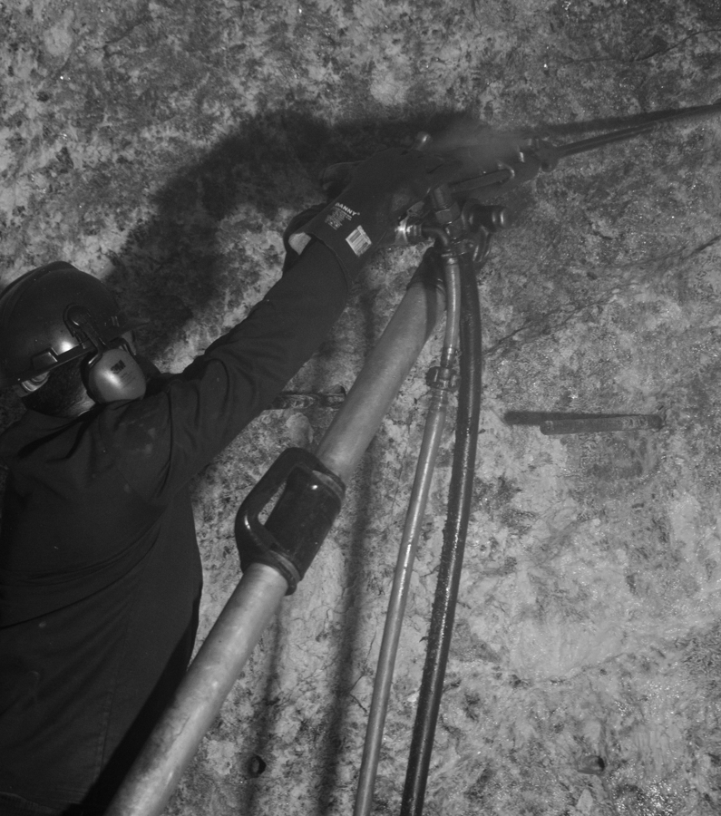 Worker Drills Dynamite Holes in Pegmatite Wall